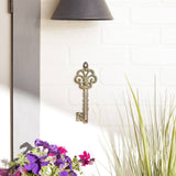 Antique metal key thermometer hung on a whitewashed brick wall near flowers