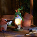 Solar powered gnome holding a glowing orb on a potting bench in the dark