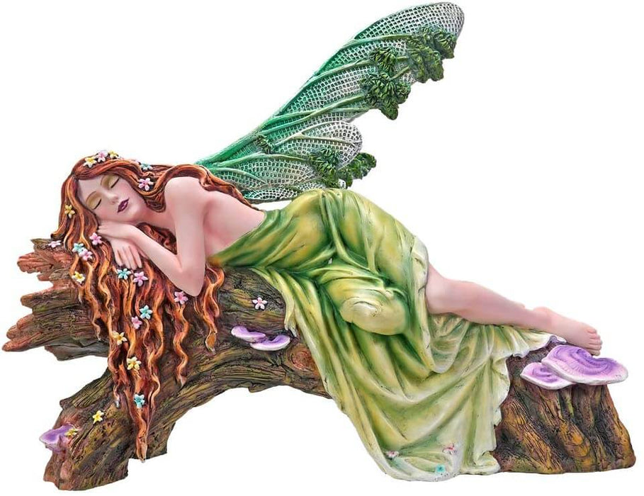The statue features a lovely pixie sleeping on a forest log. The fae lady has a green dress and leafy emerald dragonfly wings to match. Her red-brown hair is adorned with colorful flower blossoms, and purple mushrooms sprout from the wood she slumbers on.