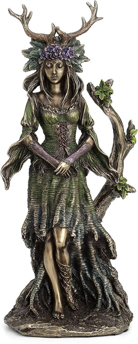 Goddess figurine in metallic bronze with shades of green and purple, wearing a crown of antlers and violets and standing by a tree