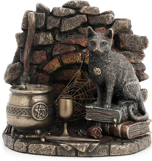 A cat wearing a pentacle sits upon a stack of thick leather-bound books. Next to the feline is a broom and bubbling cauldron, spiderweb, chalice, and athame dagger with a rose. A brick backdrop completes the piece. Front view.