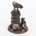 Figurine featuring two cats, one on a tall stack of books looking down at the other. Around them are a metallic skull, magic wand, and crystal ball. On a faux-wood base, done in bronzed shades.