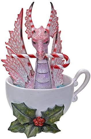 Pink and red dragon sitting in a cup, holding a candy cane in its mouth. Holly leaves and berries sit at the base of the cup.