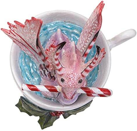 Top down view Pink and red dragon sitting in a cup, holding a candy cane in its mouth. Holly leaves and berries sit at the base of the cup.
