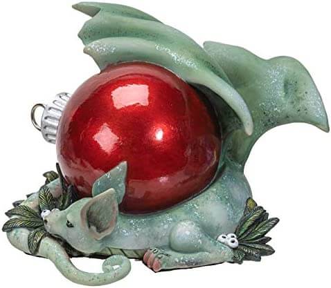 Green dragon figurine with red Christmas ornament and white berries. Shown from the side