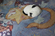 Closeup of tapestry blanket with orange butterfly cat on a star, and real white and black cat sleeping on it