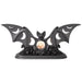Black bat tealight holder with wings outstretched, and moon phases cut out to show the candlelight. Show with a lit candle from the front