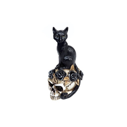 Miniature figurine of a black cat perched on a human skull decorated with black roses and gold leaves.