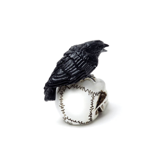 Miniature figurine of a black raven on a white human skull