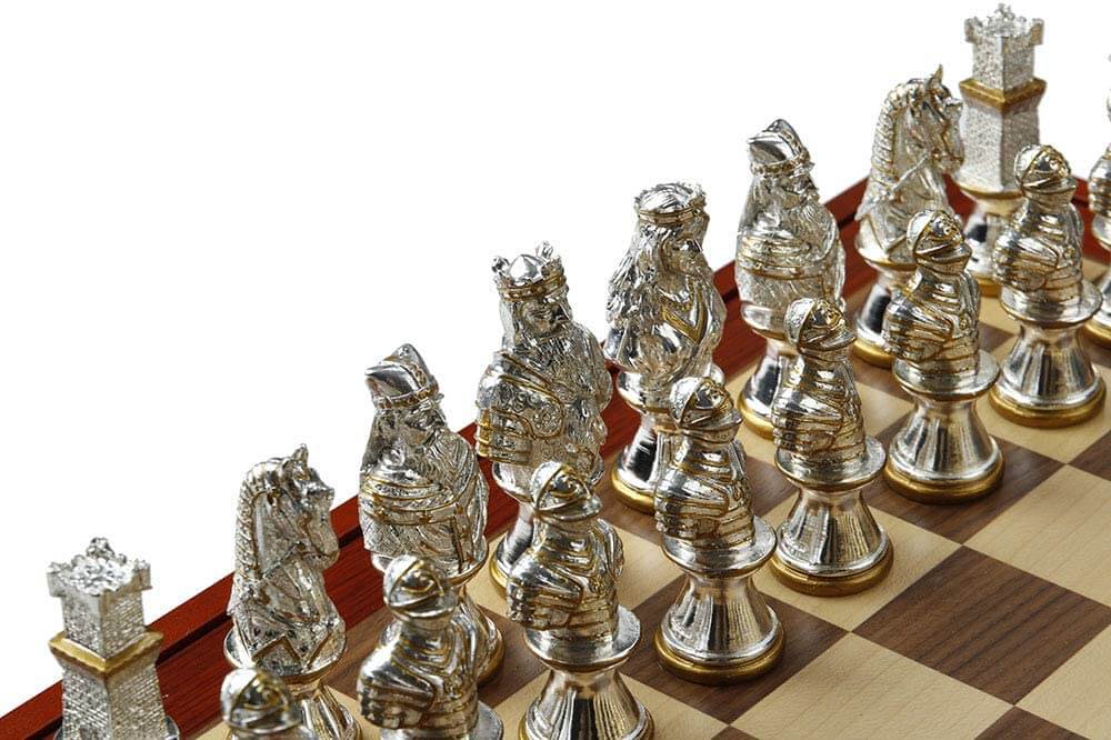 Closeup of silver chess pieces with gold accents