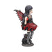 Side view - Pixie figurine wearing black and maroon holding a pumpkin. A black cat sits next to the fairy.