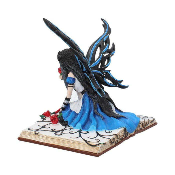 Alice in Wonderland inspired fairy with blue and black wings, a blue and white dress, and split hair colors. She sits on a storybook covered in red roses and black swirls.