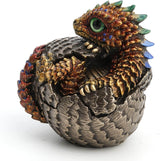 Baby dragon hatching from egg, done in shades of gold and red with blue and yellow accents and a green eye