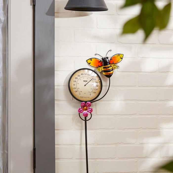 Bee thermometer with flower shown against a white wall