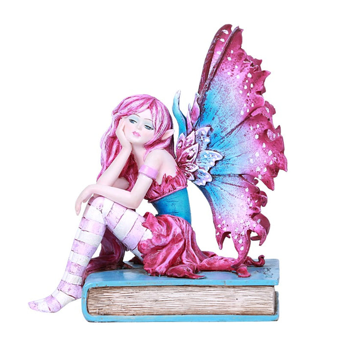 A fairy with pink and blue wings and an outfit to match sits on a cyan book