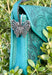 Butterfly purse hook shown on a teal purse amidst leaves