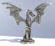 pewter dragon chained with wings spread and feamle holding the dragons chains standing next to the dragon.