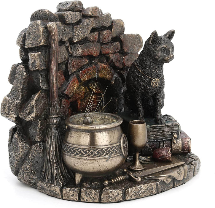 A cat wearing a pentacle sits upon a stack of thick leather-bound books. Next to the feline is a broom and bubbling cauldron, spiderweb, chalice, and athame dagger with a rose. A brick backdrop completes the piece. View from the left, better showing broom and cauldron