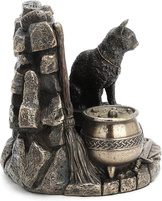 A cat wearing a pentacle sits upon a stack of thick leather-bound books. Next to the feline is a broom and bubbling cauldron, spiderweb, chalice, and athame dagger with a rose. A brick backdrop completes the piece.View from the side showing broom, cauldron, and cat