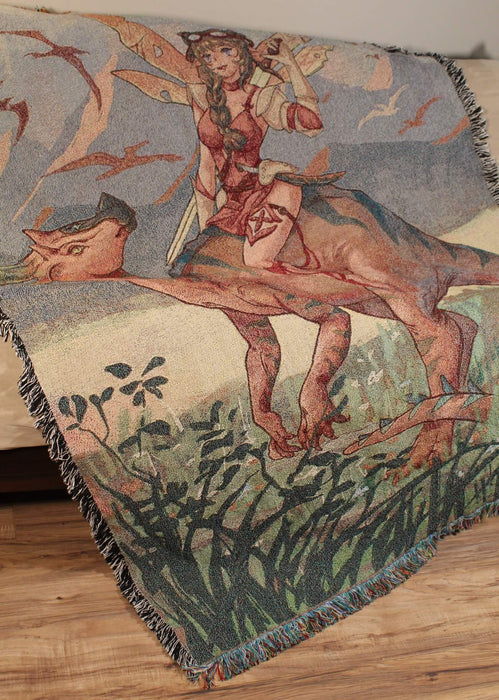 Fairy and dinosaur tapestry blanket shown draped on a couch