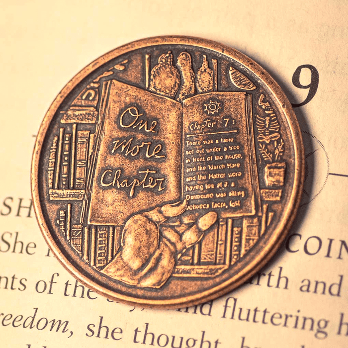 Decision maker coin featuring a book that says "One More Chapter" with a hand on one side, in copper.