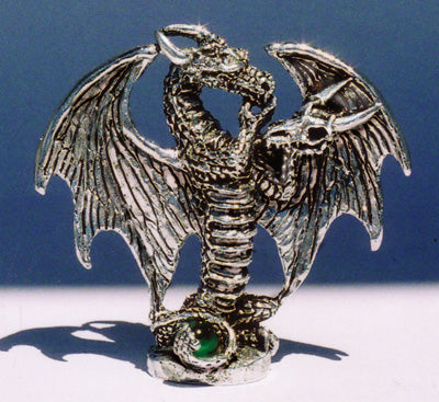 pewter dragon with hand on chin tentatively listening to Dragon skull that he is holding 