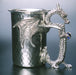 hammered pewter stein with dragon wings wrapped around stein and dragon holding gems as handle