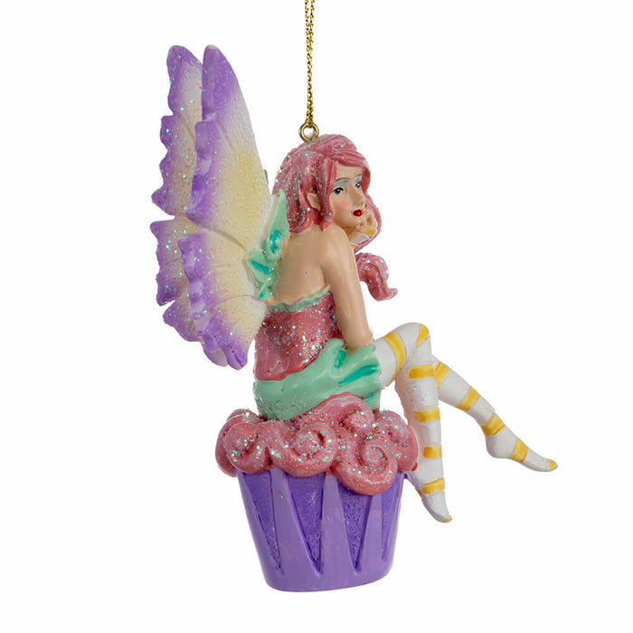 Side view of Amy Brown fairy ornament with pixie sitting on a cupcake, wearing pink, green, orange and white.