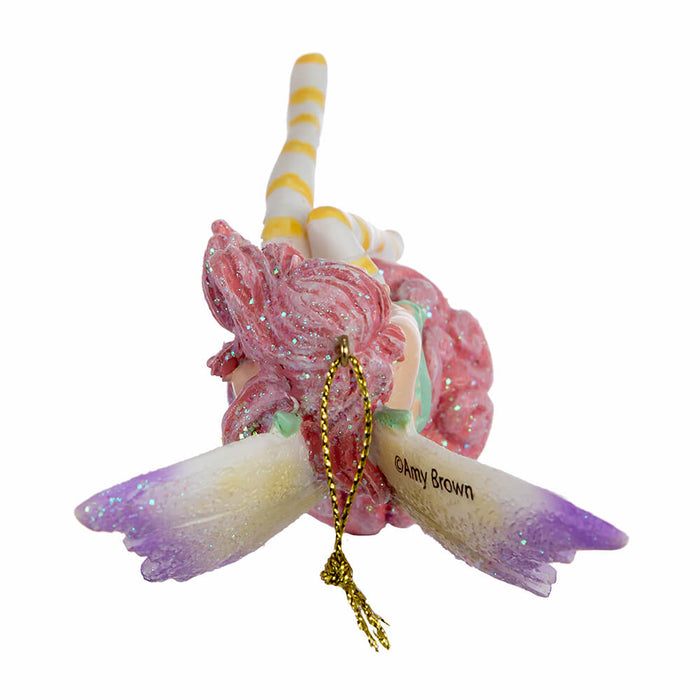 Top down view of Amy Brown fairy ornament with pixie sitting on a cupcake, wearing pink, green, orange and white.