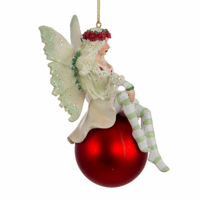 Side view of Amy Brown fairy ornament in shades of green and white, with pixie sitting on a red ornament ball.