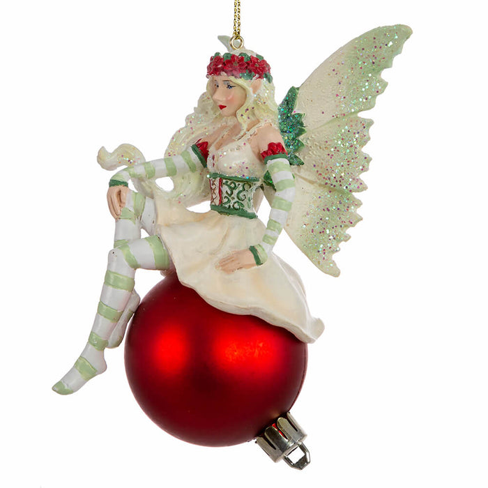 Side view of Amy Brown fairy ornament in shades of green and white, with pixie sitting on a red ornament ball.