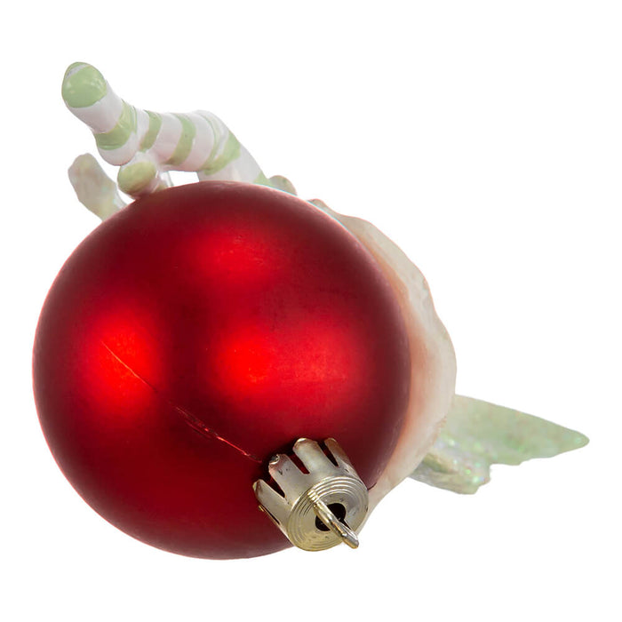 Bottom view of Amy Brown fairy ornament in shades of green and white, with pixie sitting on a red ornament ball.
