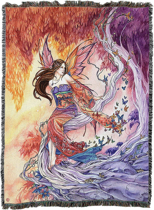 A tapestry blanket  with fantasy art. A colorful fairy sits under a red-orange leaved tree, next to a purple forest. Butterflies in many colors rise up.
