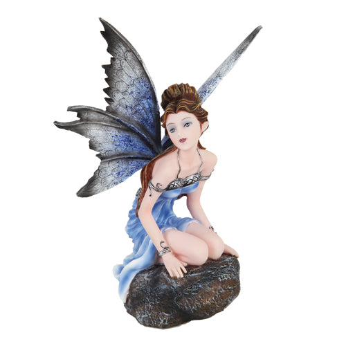 A stunning fairy with pale skin and brown hair kneels on a rock. She has a blue dress with silver accents, and her wings are indigo and black.