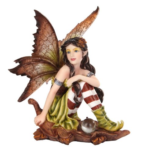 Fairy figurine, the pixie sits on a brown oak leaf with a crystal ball. She has brown wings and a green dress with brown and white striped stockings, and brunette hair