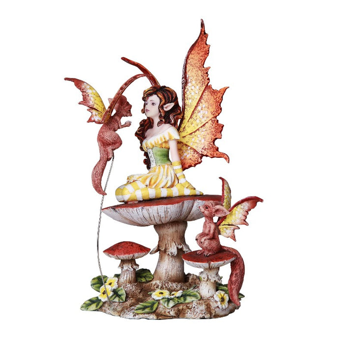 A dragon in yellow and white stripes with a green bodice and auburn hair sits on a red mushroom. Two little flying friends keep her company