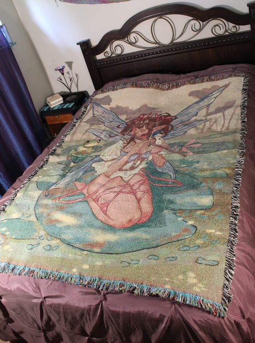 Woven fairy playing flute tapestry blanket displayed on a queen sized bed