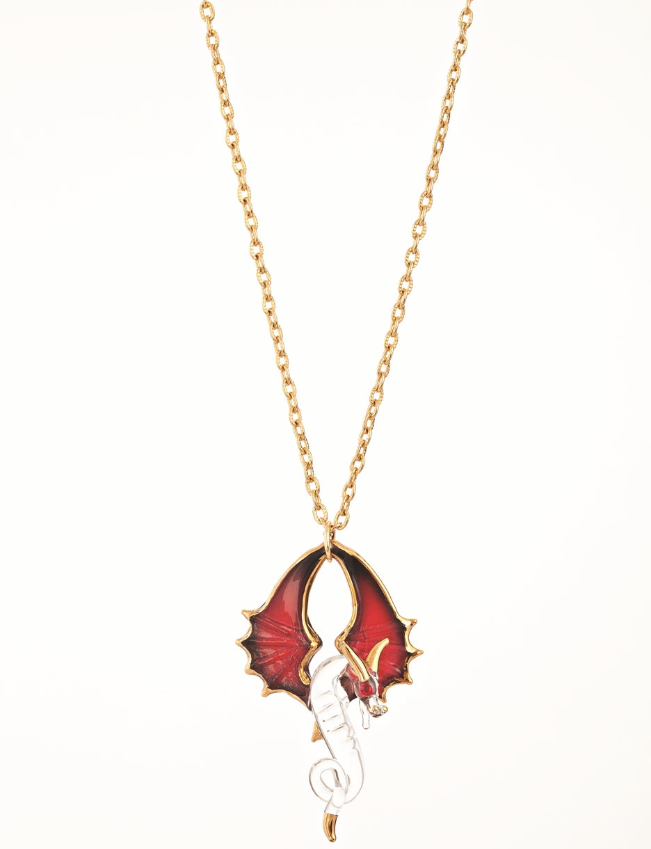 Glass necklace charm features a clear dragon with red wings curving upwards, and gold accents. Red crystal eyes sparkle, and the pendant hangs from a gold chain