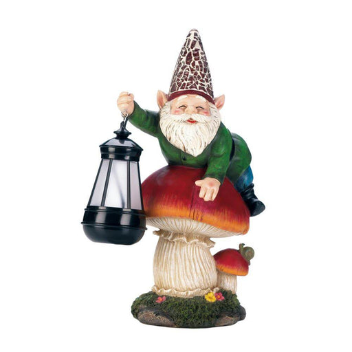 Gnome in green and a fancy hat sits on a red mushroom, accompanied by a tiny snail on another toadstool. The garden gnome holds a lantern that glows via solar power 