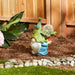 Gnome with solar orb flower pot shown in garden setting with bluebirds on his hat