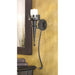 Torch Gothic Candle Sconce hung on a tan wall with a lit pillar candle