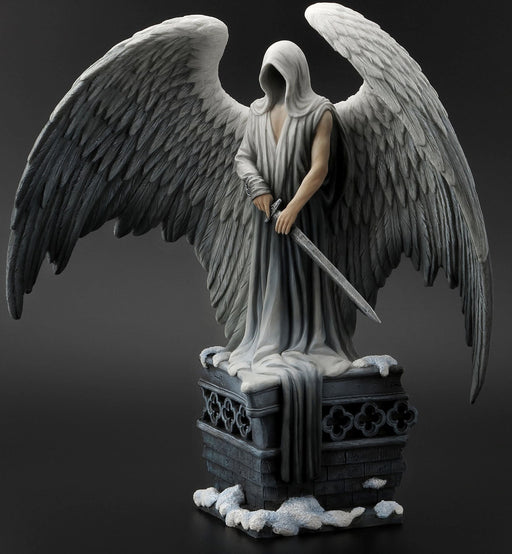 Guardian angel statue with feathered wings outspread, holding a sword and standing on a stone pillar with snow