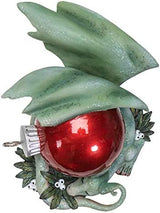 Green dragon figurine with red Christmas ornament and white berries. Shown top down