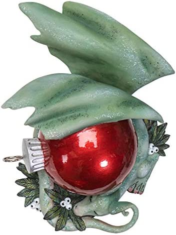 Green dragon figurine with red Christmas ornament and white berries. Shown top down