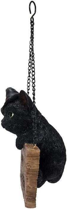 Black Kitten in witch hat hanging on a "Happy Halloween" sign, with chain for displaying. Viewed from the side, kitten hangs over the edge