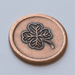 Copper lucky coin showing four leaf clover