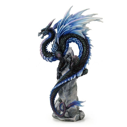 The dragon perches upon a rocky crag, mouth open and eyes alert. It has iridescent scales and accents of sapphire blue fading to white, reminiscent of snow and ice. Wings splay out above the dragon's back, and its tail curls and spirals gracefully down the rocks.