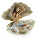 Mermaid with pastel tail and brown hair sitting in a seashell