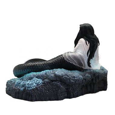 Mermaid with black hair and scales in pool of water with skulls