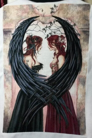 Cross stitch of fairy sisters with black feathered wings. One in a black dress, one in a maroon dress